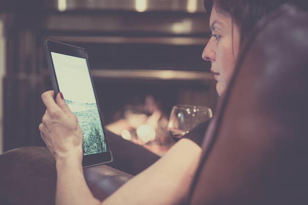 jeune femme utilisant une tablette numérique par cheminée - bright brightly lit vibrant color burning photos et images de collection