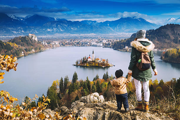 Traveling family looking on Bled Lake, Slovenia, Europe Family travel Europe. Mother with son looking on Bled Lake. Autumn or Winter in Slovenia, Europe. Top view on Island with Catholic Church in Bled Lake with Castle and Mountains in Background. gorenjska stock pictures, royalty-free photos & images