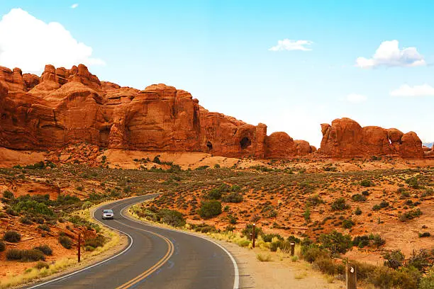 A single car driving on a scenic road at Arches National Park.
