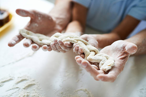 Father and son holding a braid of dough
