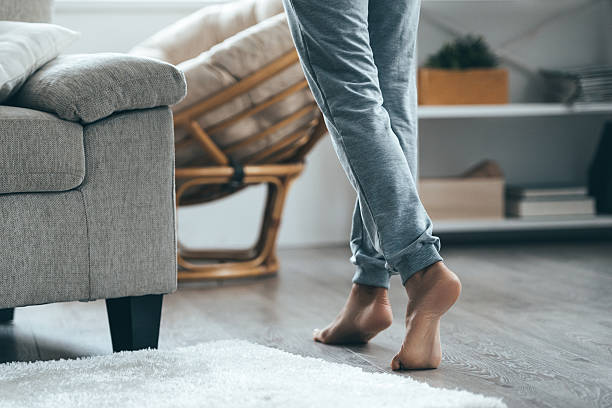 Warm floor concept. Close-up of female legs stepping by hardwood floor at home barefoot stock pictures, royalty-free photos & images