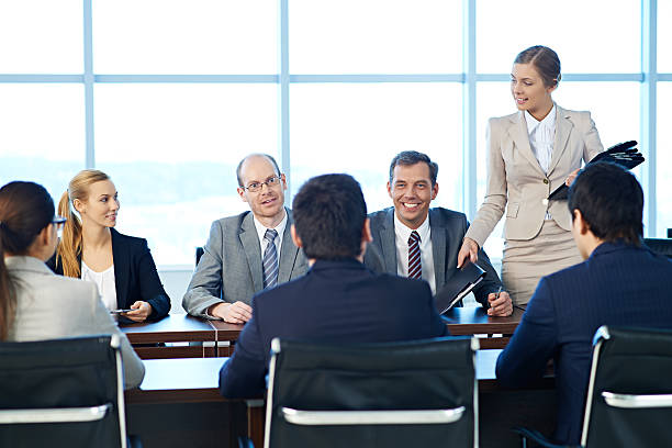 Shareholders having a meeting, a secretary giving out folders with documents Shareholders having a meeting, a secretary giving out folders with documents shareholders meeting stock pictures, royalty-free photos & images