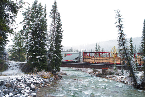 Lake Louise, Canada - September 20, 2016: Canadian Pacific Railway wagon in snow. A freight train crosses the Bow River in Lake Louise Village, Alberta, Candian Rockies, during the first snowfall of the year. The wagon is clearly labelled Canadian Pacific Railway, the transport system that shaped so much of the way this region was settled in the past.