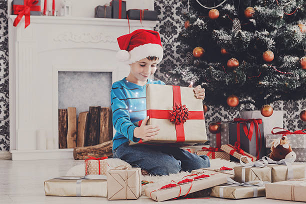 istock Cute happy boy in santa hat unwrapping christmas presents 624630566