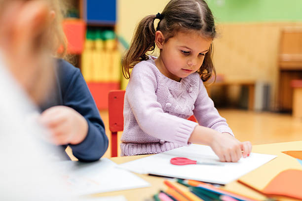 istock Happy Little Girl using scissors in kindergarten. 624645982