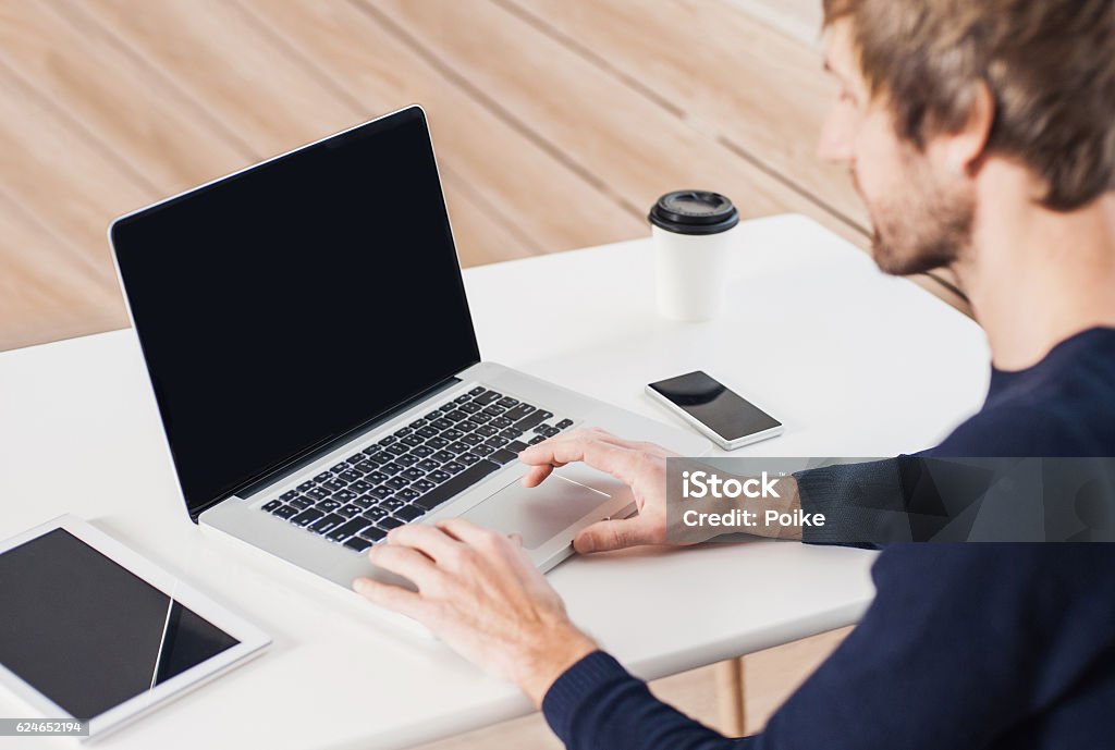 Place of work, man using laptop computer Young man using laptop computer at his desk Computer Monitor Stock Photo