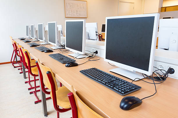 Computers in classroom on high school Computer education in classroom on high school. On this long table you see many desktop computers with keyboards and computer mouses. Also many chairs for the children to sit and work with the computer. In this classroom the students get computer lessons so they get prepared for our digital society as a lifestyle computer lab stock pictures, royalty-free photos & images