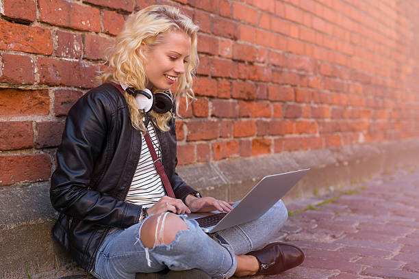 istock Hipster sitting on the ground in the city and working on computer 624654460