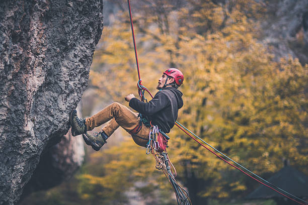 Time to go down Man is belaying from the cliff crag stock pictures, royalty-free photos & images