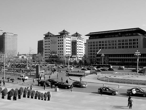 Beijing, China - March 24, 2008: Black and white image of the Chang'an Avenue in Beijing, China in front of the Oriental Plaza on a morning in spring. In the foreground are the stairs leading up to the Oriental Plaza housing two stories of stores (many selling luxurious expensive goods), bars and restaurants as well as (above the two lowest basement stories) the Grand Hyatt hotel and offices. Pedestrians are seen walking on the sidewalk. A group of taxi cabs are waiting along the sidewalk. The traffic is running smoothly in both directions of the 10-line avenue. Large buildings are seen in the background. Chang'an Avenue (\