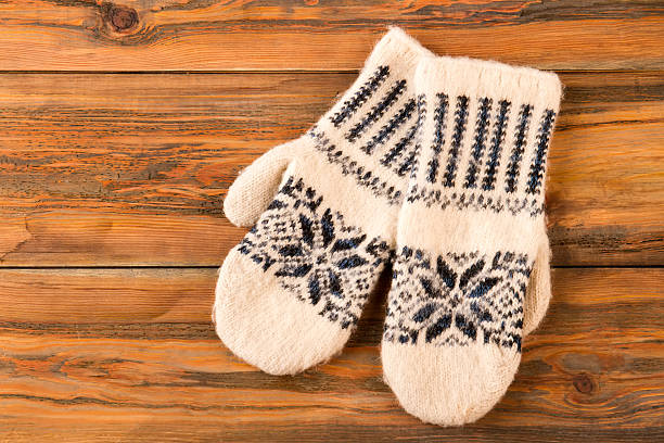 istock White mittens with ornament on wooden background. 624674844