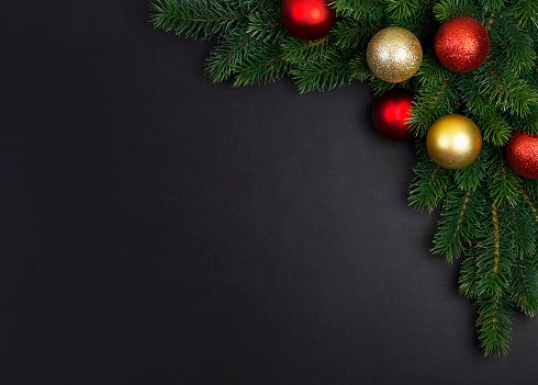 The branch of a Christmas tree with Christmas decorations on a black background