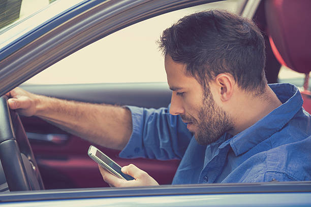 hombre usando mensajes de texto en el teléfono móvil mientras conduce un coche - driving text messaging accident car fotografías e imágenes de stock