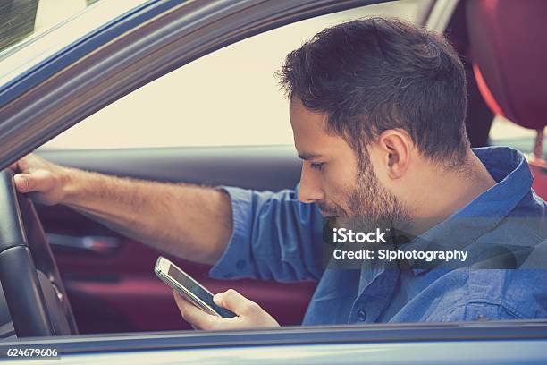 Man Using Texting On Mobile Phone While Driving A Car Stock Photo - Download Image Now