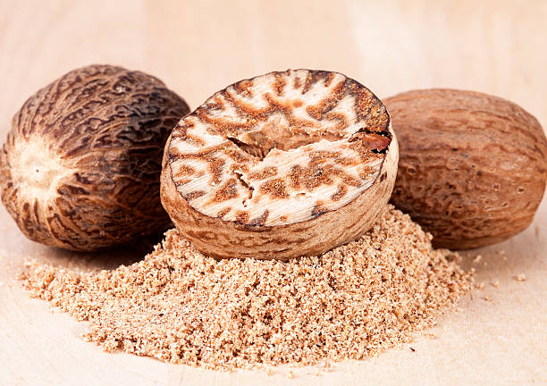 istock Nutmeg , whole and half on wooden plank, close up 624679968