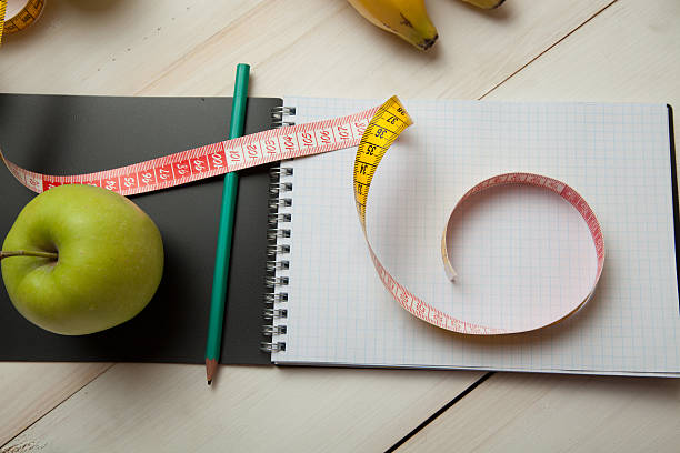 istock Green apples with measuring tape on a white wooden table 624681258