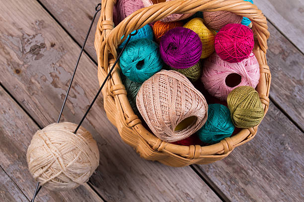 istock Color threads, knitting needles on the wooden boards. 624682298