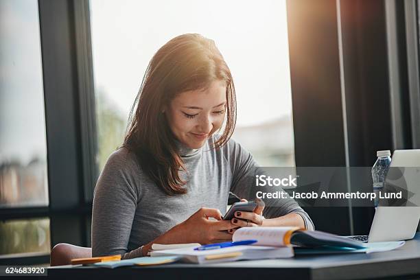 Asiatische Mädchen Mit Handy In Der Bibliothek Stockfoto und mehr Bilder von Universitätsstudent - Universitätsstudent, Smartphone, Asiatischer und Indischer Abstammung