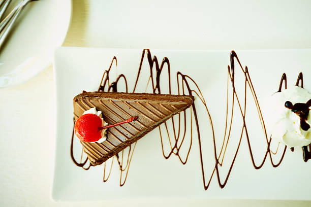 Piece of chocolate cake with cherry on table in coffeeshop