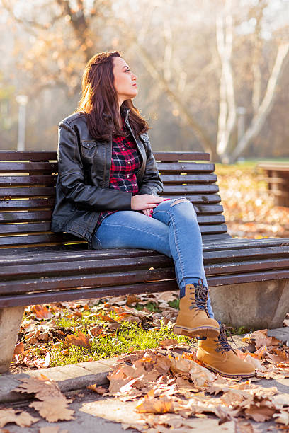 istock Young woman sitting on a bench in the park 624685204
