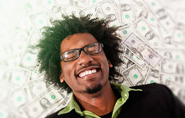 istock Ecstatic young man lies on pile of dollars grinning joyfully 624696292