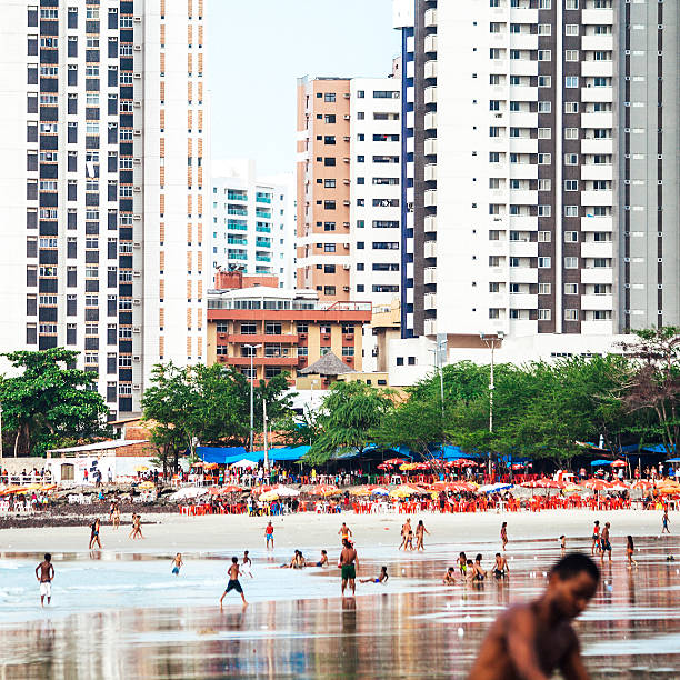 Sao Luis, Brazil - February 3, 2013: Popular public beach in town called Praia Ponta D'Areia is full of local people playing football, relaxing, sunbathing and swimming.
