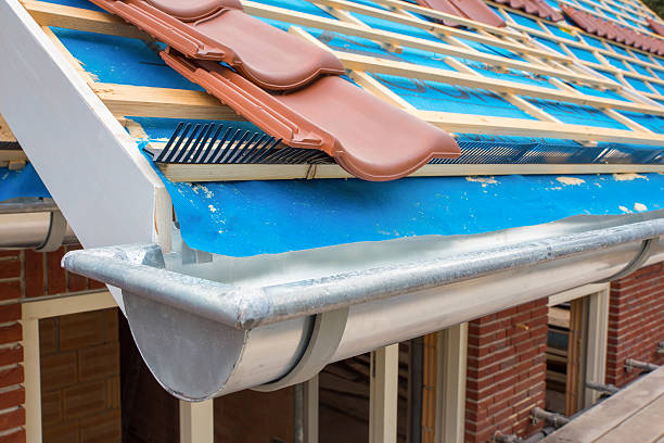 Zinc gutter and tiles on roof pitch of house Zinc gutter and roof tiles on new house. I took this photo to show how a house uses water management for the rain water that is falling on the roof. Because this is a new house, not all the roof tiles are in place yet. The water in the metal gutter will stream into the drainpipe and then into the ground. zinc element stock pictures, royalty-free photos & images