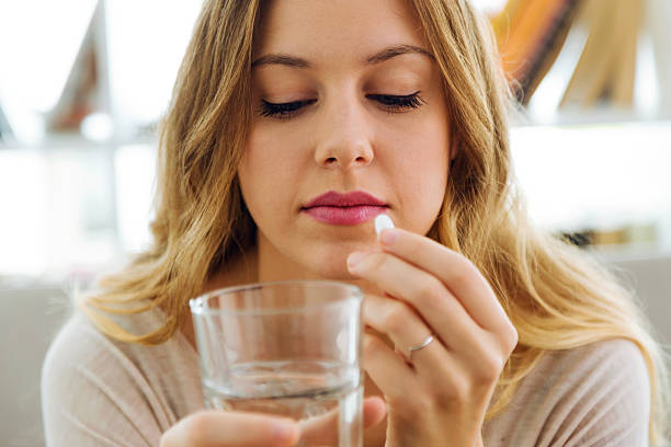istock Depressed young woman taking pills at home. 624698450