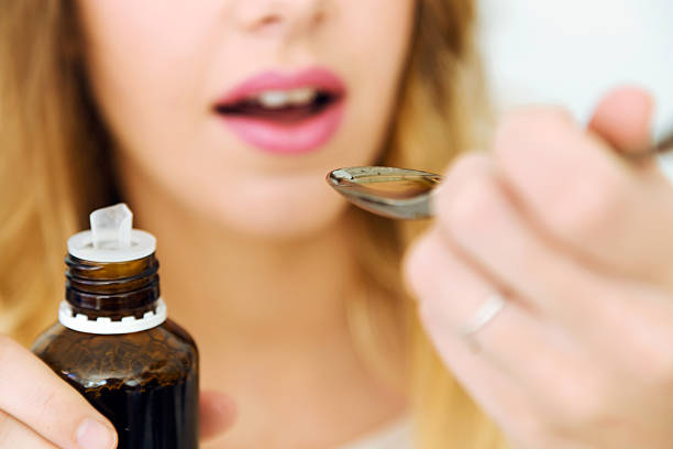istock Young woman taking medicine on spoon at home. 624700692