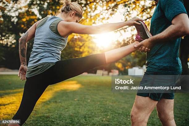 Trainer Helping Woman In Leg Stretching Workout Stock Photo - Download Image Now - Fitness Instructor, Outdoors, Exercising