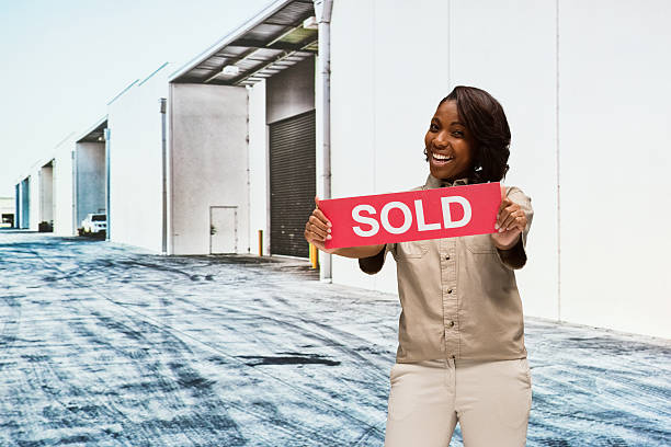 Extreme close-up on the word 'Sold', in bright red on a real estate sign posted in the street.