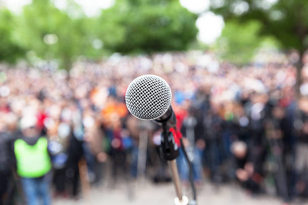 Political protest. Public demonstration. Political Rally. Microphone in focus against blurred crowd. political rally photos stock pictures, royalty-free photos & images