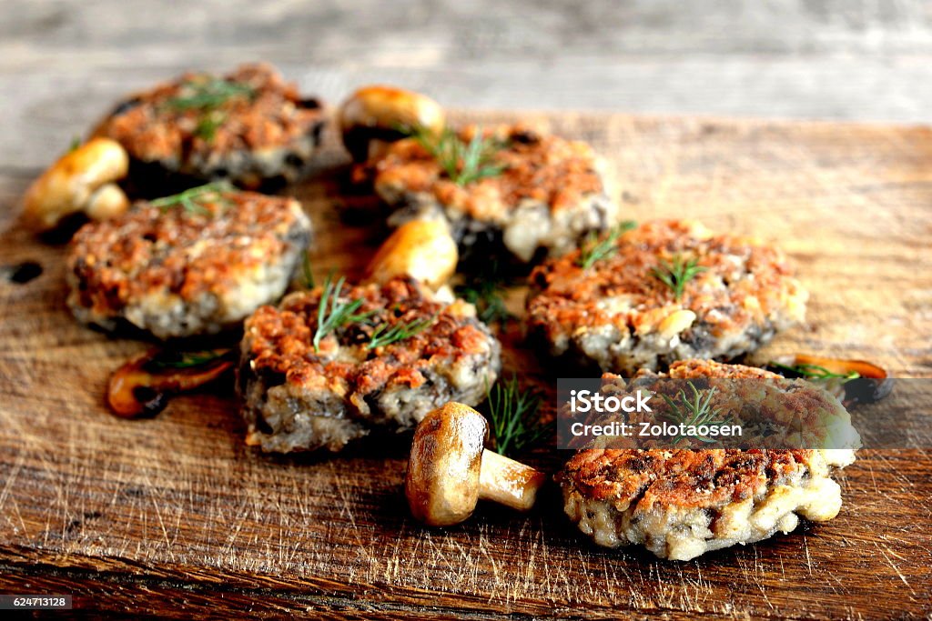 Fried mushroom cutlets Fried mushroom cutlets decorated with dill on a wooden background. Agaricus recipe. Vegetarian and diet food Burger Stock Photo