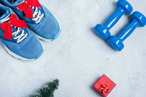 composición deportiva navideña con zapatos, mancuernas y caja de regalo roja - holiday healthy lifestyle weight christmas fotografías e imágenes de stock