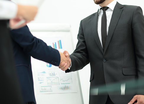 closeup investor shakes hands with the speaker after a successful financial presentation. photo on the background of the financial schedule.the photo has a empty space for your text
