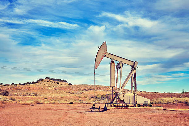 Retro toned picture of an old oil pump. Retro toned picture of an oil pump, old industrial equipment on arid soil. gasoline photos stock pictures, royalty-free photos & images