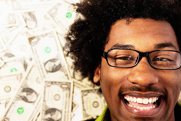 istock Grinning young man surrounded by cash cannot believe his luck 624723676