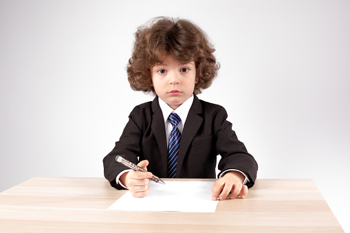 Little boss with a clean sheet of paper and a pen. Gray background. Close-up