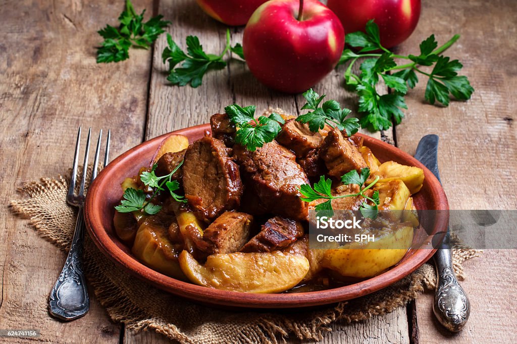 Pork stew with apple sauce Pork stew with apple sauce, vintage wooden background, selective focus Duck Meat Stock Photo