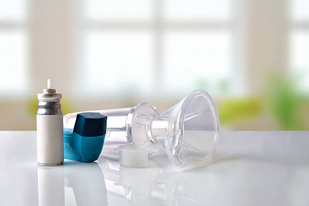 Cartridge inhaler and chamber and mask in room front view Cartridge, blue medicine inhaler, inhalation chamber and silicone mask on white glass table in a room. Front view. Horizontal composition asthmatic stock pictures, royalty-free photos & images