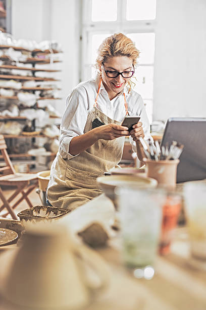 istock Potter entrepreneur using laptop and mobile phone  in workshop 624745640
