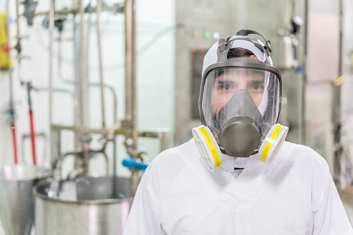 Man working at a food processing plant wearing protection facemask and looking at the camera