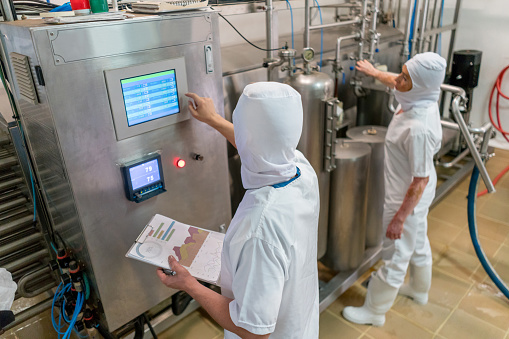 Men working at a food factory and operating a food processing machine