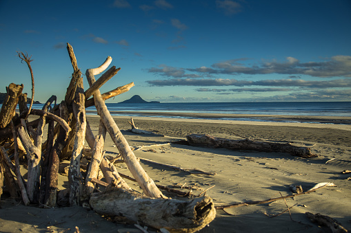 A pyramid of driftwood on Ohope Beach, looking out to Moutohora Island in the Bay of Plenty. Still frame from time lapse video 615130002.