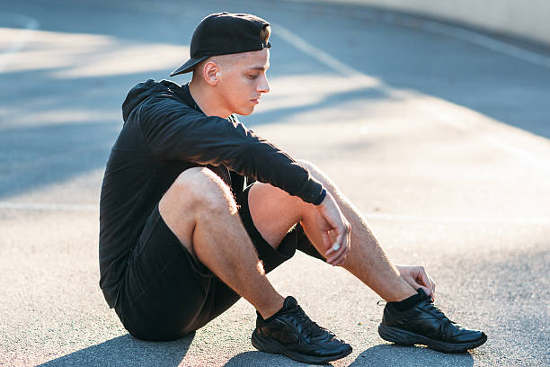 istock Young sporty man sitting on ground at stadium 624750636
