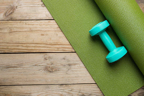 dumbbell and yoga mat on wood table