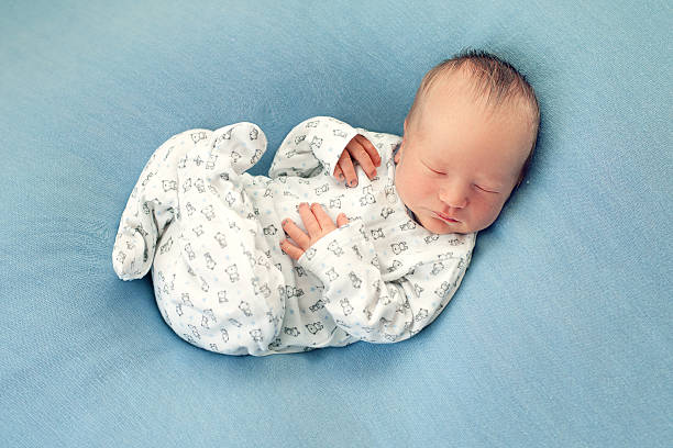 istock Newborn boy asleep on a blue background in white pajamas 624771798