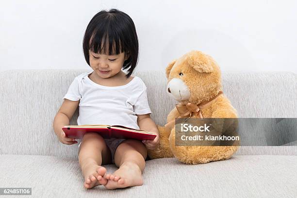 Asian Chinese Little Girl Reading Book With Teddy Bear Stock Photo - Download Image Now