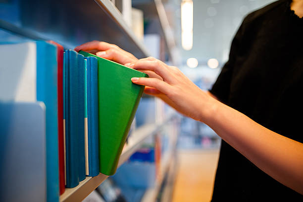 istock Woman hand in a library taking a book 624854432