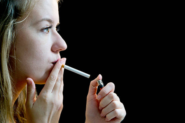 istock Woman lighting cigarette over dark background insade 624867952